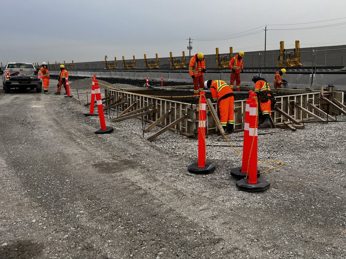 Crew building the bridge footing formwork beside the tracks, March 2026