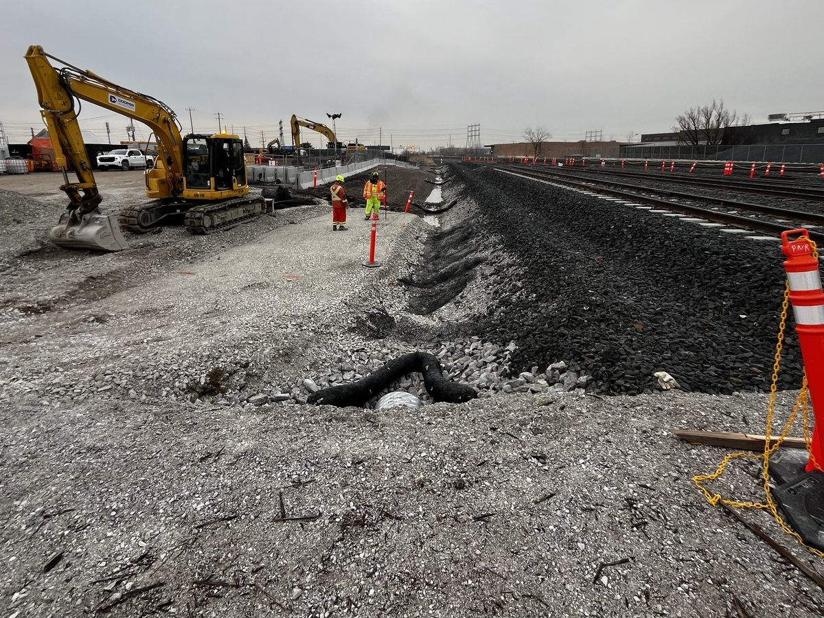 Excavators and a survey crew beside the GO rail corridor at Woodbine